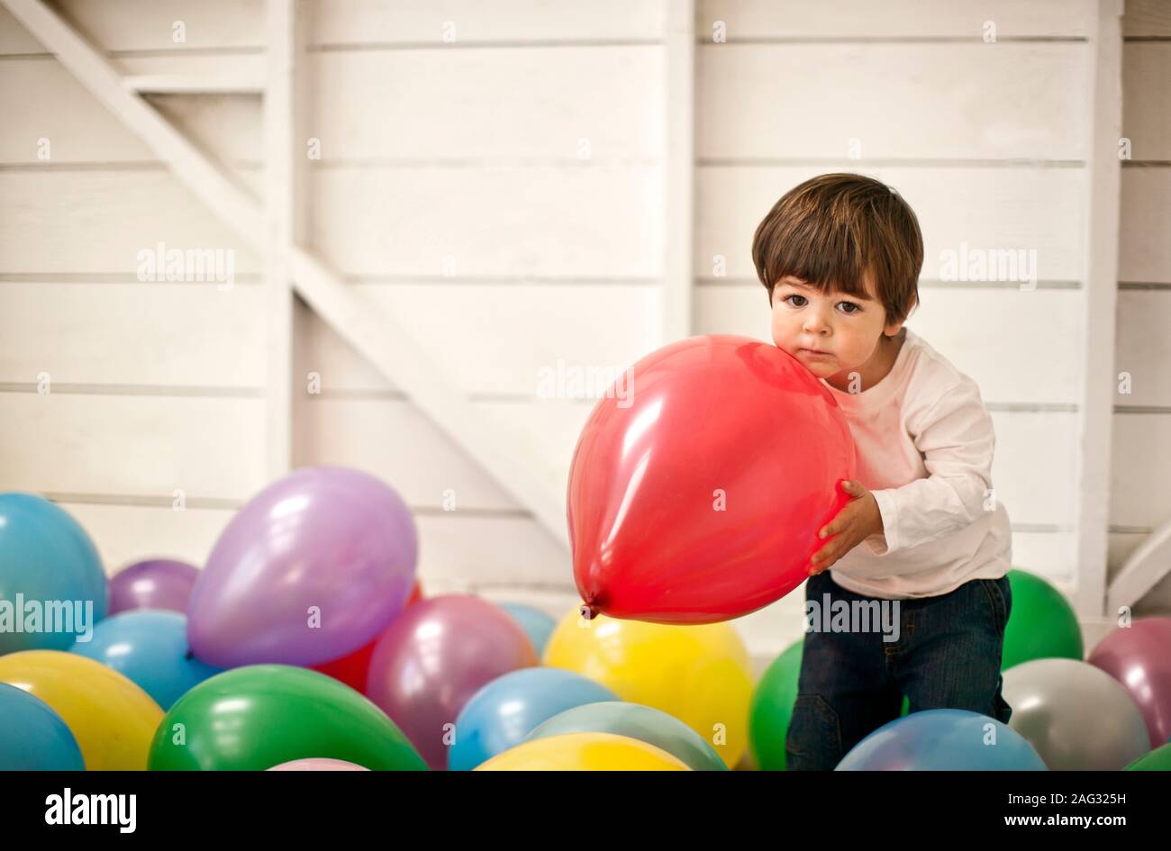 Little Boy spielen sich in einem Raum voller Luftballons. Stockfoto