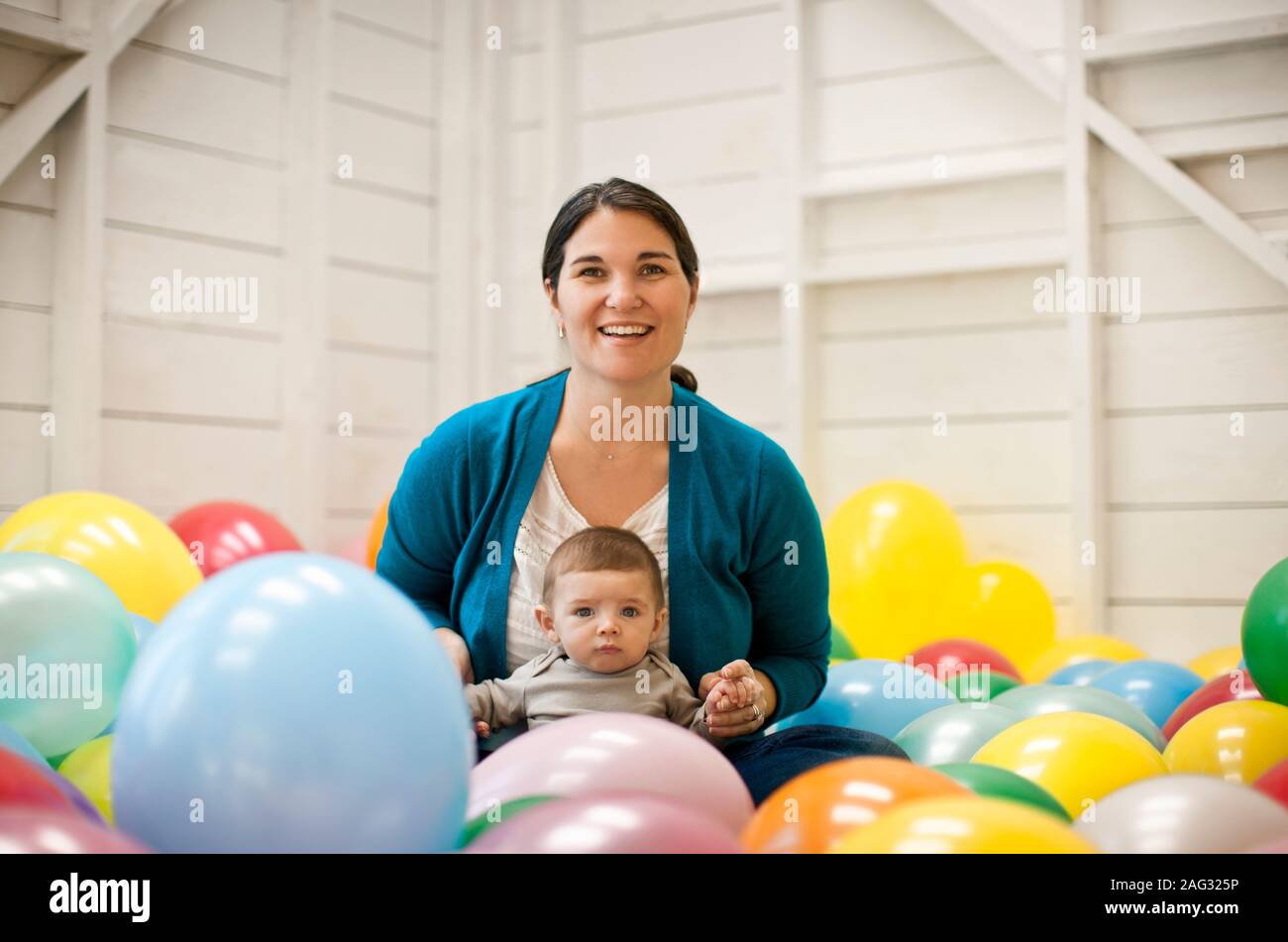 Frau und ihr Baby Sohn sitzen in einem Raum voller Luftballons. Stockfoto