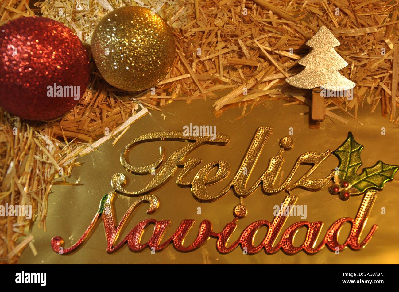 Frohe Weihnachten auf Spanisch lateinische Sprache. Weihnachten gretting Karte. Kugeln, Stroh und goldenen Verzierungen. Stockfoto