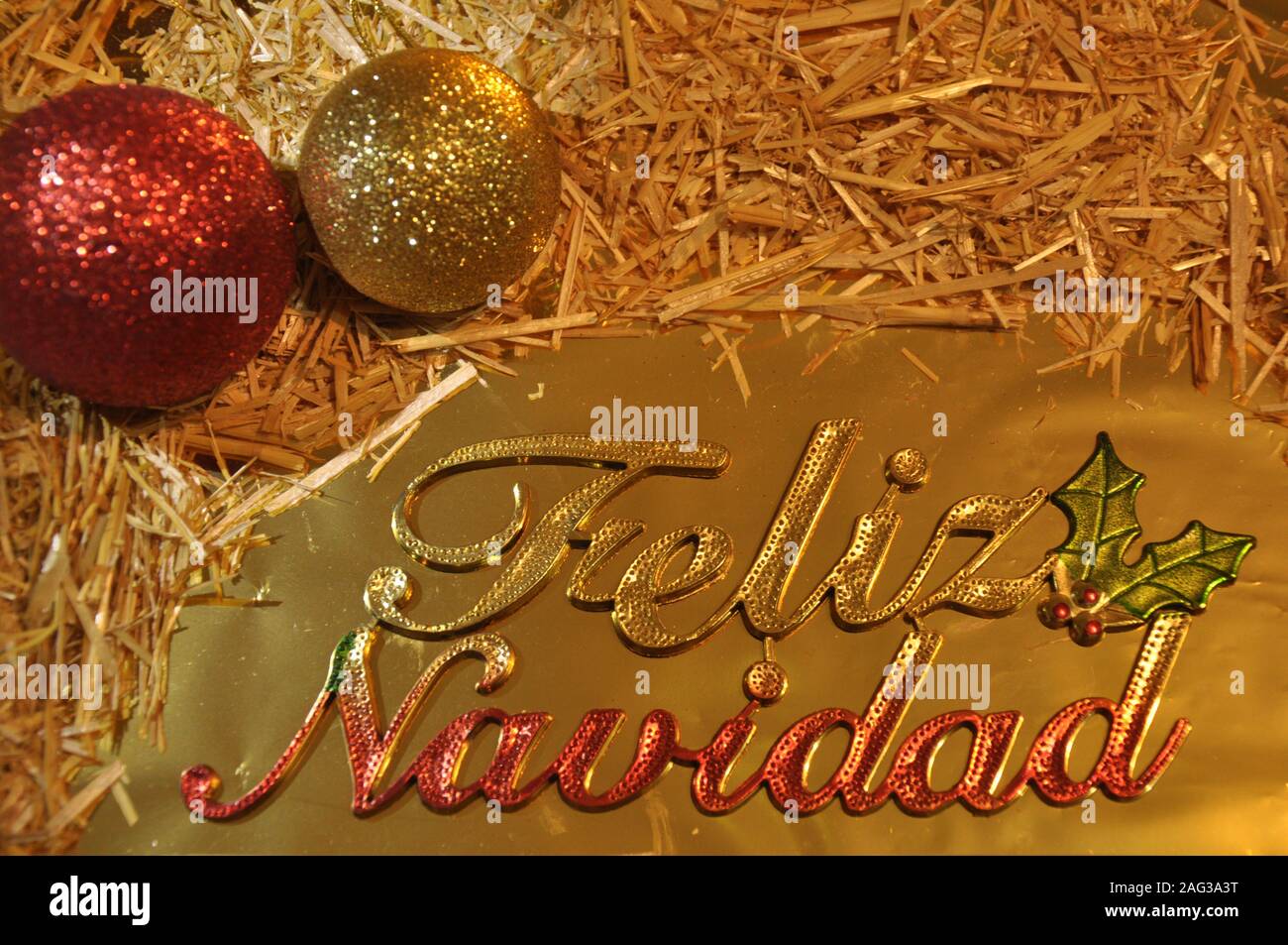 Frohe Weihnachten auf Spanisch lateinische Sprache. Weihnachten gretting Karte. Kugeln, Stroh und goldenen Verzierungen. Stockfoto