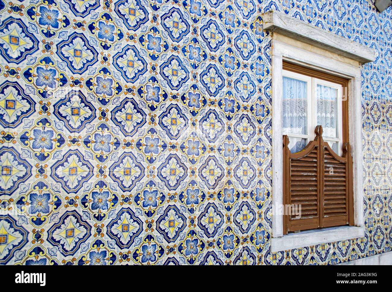 Schuss von orangefarbenen und blauen Mosaikfliesen, die eine Wand bilden Mit einem Fenster in der Mitte Stockfoto