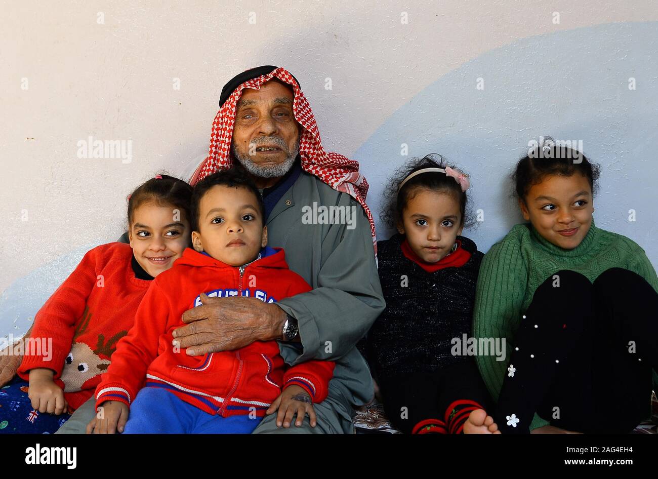 (191218) - GAZA, Dez. 18, 2019 (Xinhua) - suleiman Abu-Namous sitzt mit seiner Familie im Flüchtlingslager Jabalia im nördlichen Gazastreifen, Dez. 17, 2019. Suleiman Abu-Namous aus Gaza vor kurzem stieß einen Seufzer der Erleichterung nach Anhörung, dass das Mandat der Vereinten Nationen für Palästinaflüchtlinge im Nahen Osten (UNRWA) für weitere drei Jahre verlängert werden. Die UNRWA hat ein rettungsseil und ein Anbieter von grundlegenden Dienstleistungen für rund fünf Millionen palästinensischen Flüchtlinge in der Region, einschließlich der 110 Jahre alte Mann und seine Familie. Gehen MIT "Funktion: Palästinensische re Stockfoto