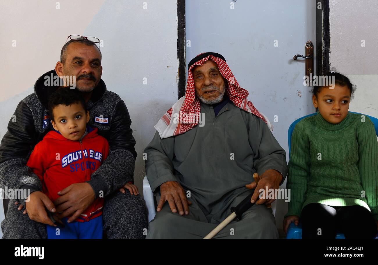 (191218) - GAZA, Dez. 18, 2019 (Xinhua) - suleiman Abu-Namous (C) sitzt mit seiner Familie im Flüchtlingslager Jabalia im nördlichen Gazastreifen, Dez. 17, 2019. Suleiman Abu-Namous aus Gaza vor kurzem stieß einen Seufzer der Erleichterung nach Anhörung, dass das Mandat der Vereinten Nationen für Palästinaflüchtlinge im Nahen Osten (UNRWA) für weitere drei Jahre verlängert werden. Die UNRWA hat ein rettungsseil und ein Anbieter von grundlegenden Dienstleistungen für rund fünf Millionen palästinensischen Flüchtlinge in der Region, einschließlich der 110 Jahre alte Mann und seine Familie. Gehen mit 'Feature: palestinia Stockfoto