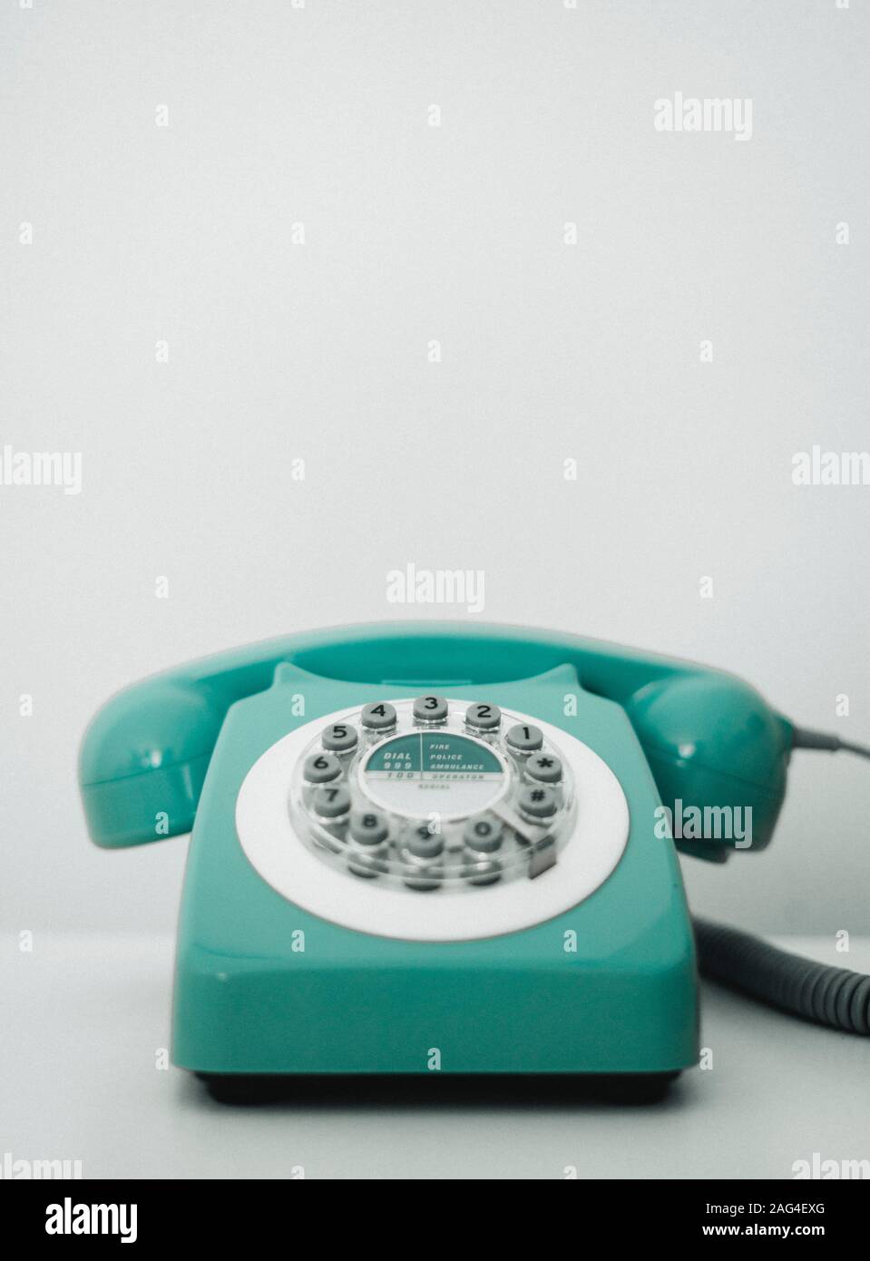 Vertikale Aufnahme eines türkisfarbenen Retro-Telefons auf einem weißen Hintergrund Stockfoto