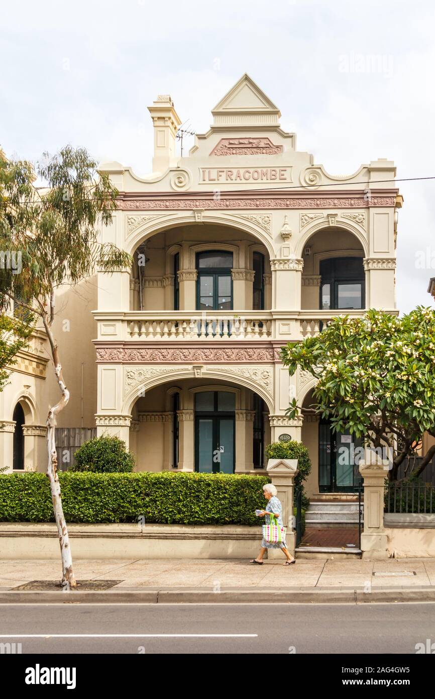Sydney, Australien - 26. März 2013: Eine Frau geht Vergangenheit ein typisches Haus in den Vorstädten. Dieses architektonische Stil war sehr beliebt. Stockfoto