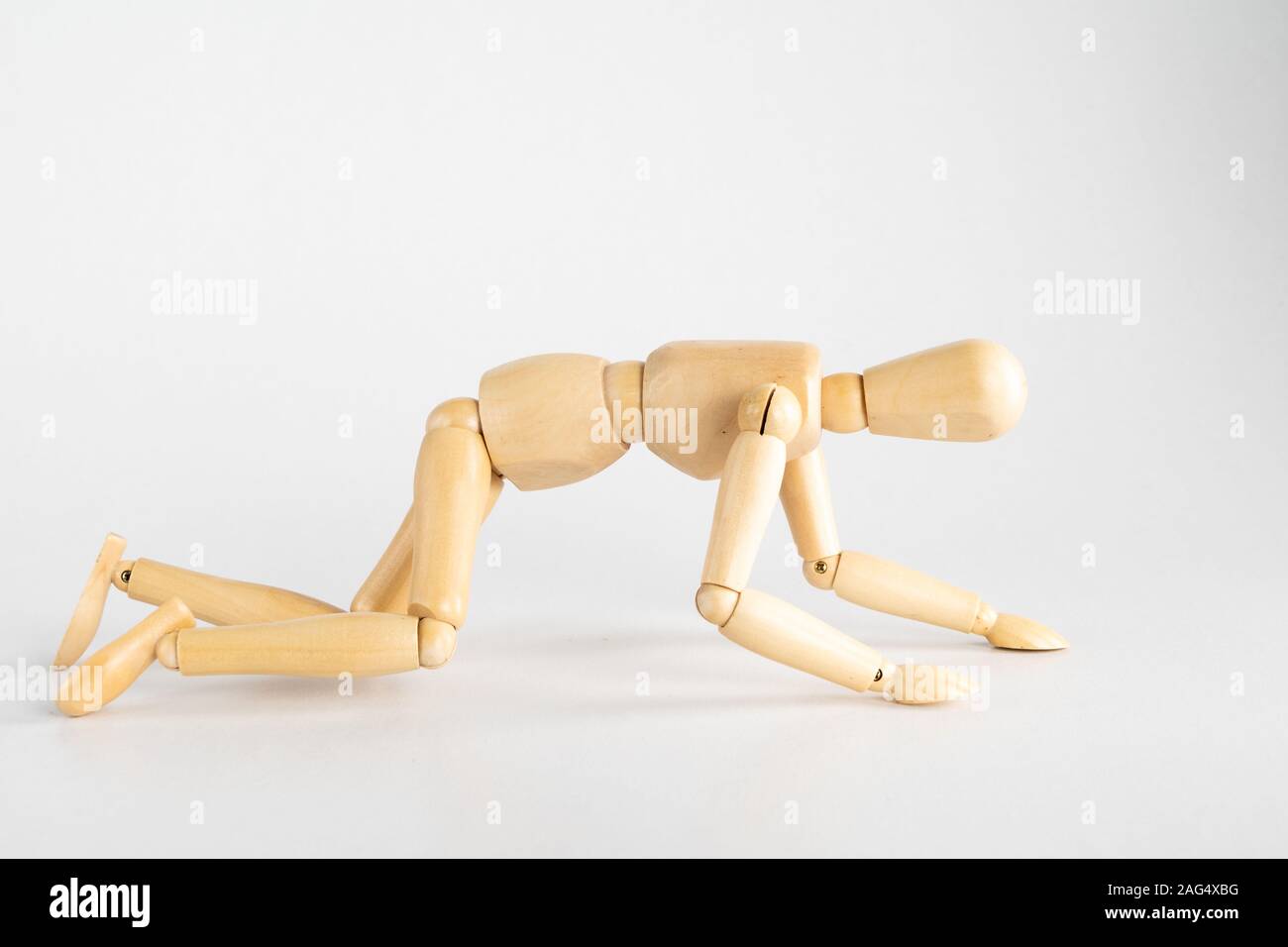 Holzpose Puppe posierte wie kriechen auf einem weißen Hintergrund Stockfoto