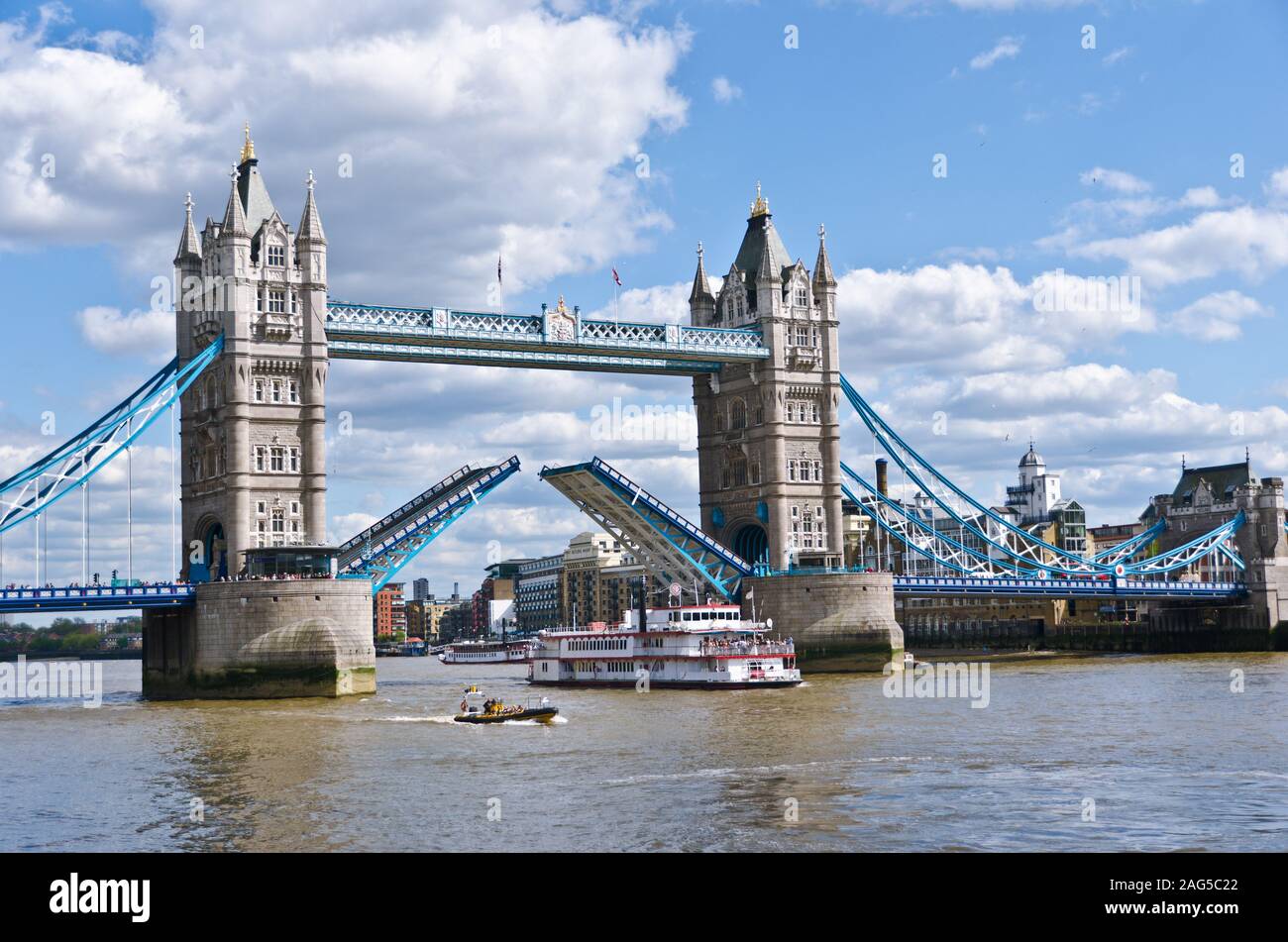 Boot segeln unter der Tower Bridge in London mit einem wolkiger Himmel im Hintergrund Stockfoto