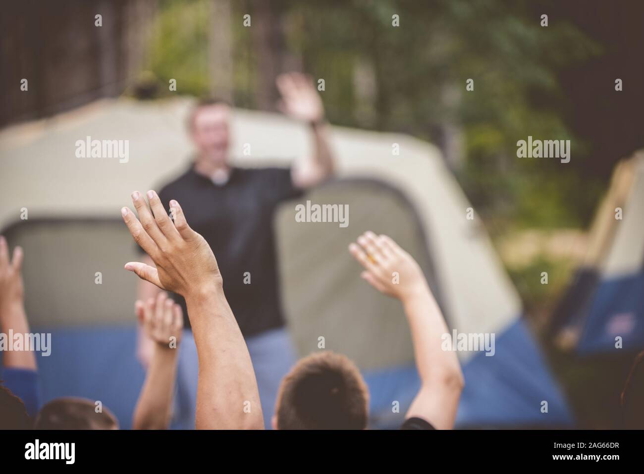 Nahaufnahme von Kindern mit den Händen nach oben mit einem Verschwommener Bus in der Ferne im Lager Stockfoto