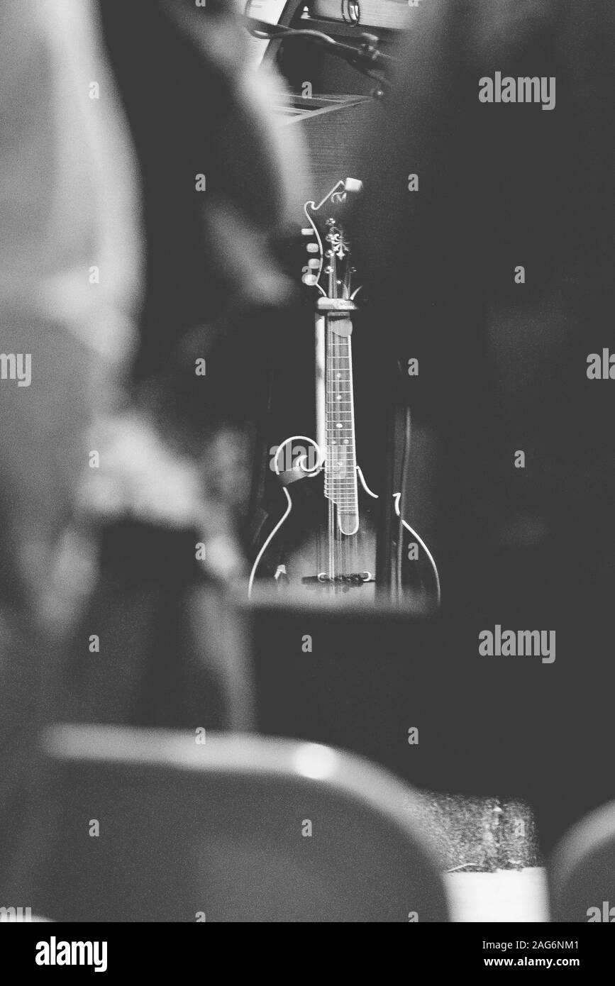 Graustufen-Vertikalaufnahme einer E-Gitarre, die sich gegen eine lehnte Wand Stockfoto