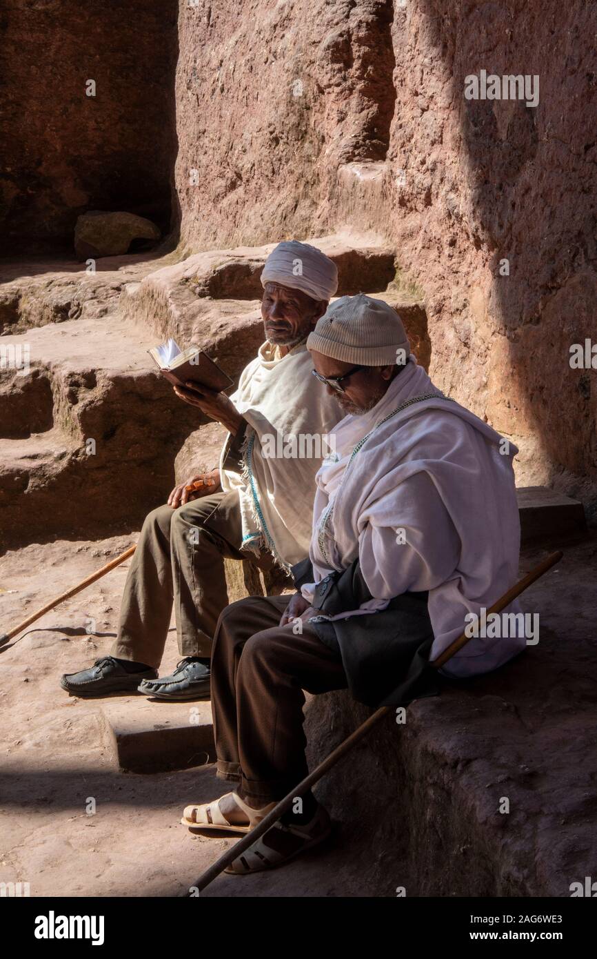 Äthiopien, Amhara-region, Lalibela, Wette Maryam Kirche Hof, zwei Priester Lesung Evangelium im Sonnenschein Stockfoto