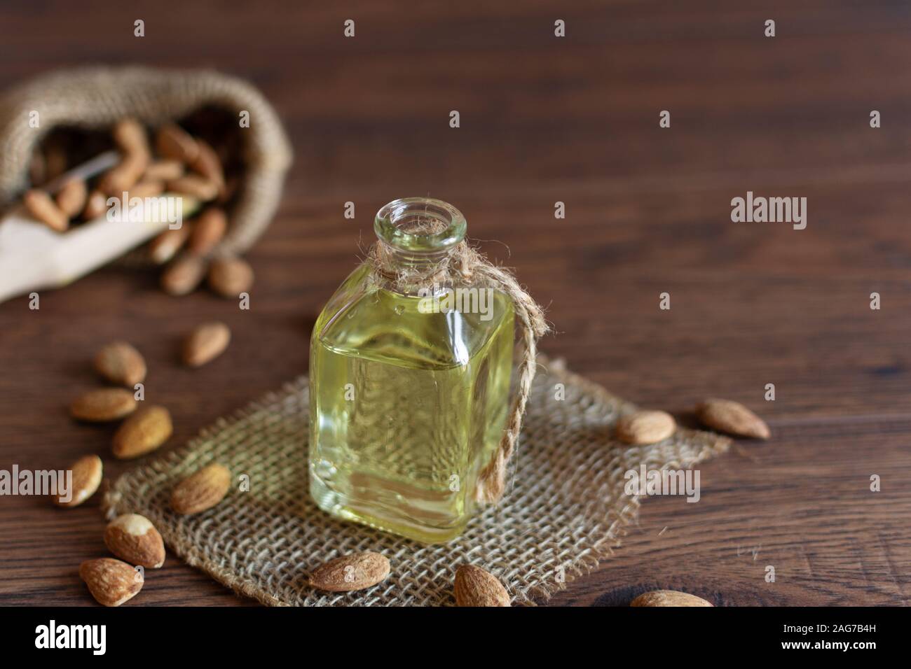 Mandelöl in kleinen Fläschchen und Mandel Muttern auf Holz- Hintergrund. Stockfoto