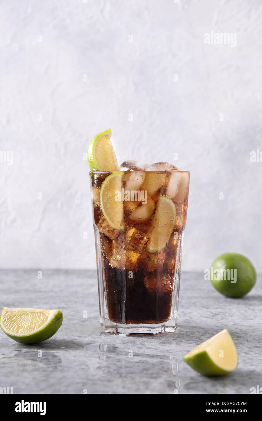 Cocktail Cuba Libre oder Long Island Iced Tea mit Rom, Cola, Kalk und Eis im Glas auf grauem Stein Tabelle. Vertikale Format. Stockfoto