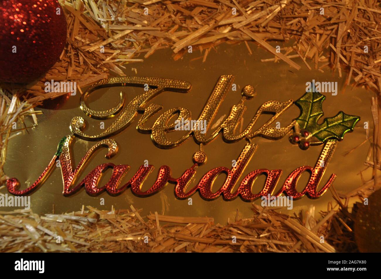 Frohe Weihnachten auf Spanisch lateinische Sprache. Weihnachten gretting Karte. Kugeln, Stroh und goldenen Verzierungen. Stockfoto