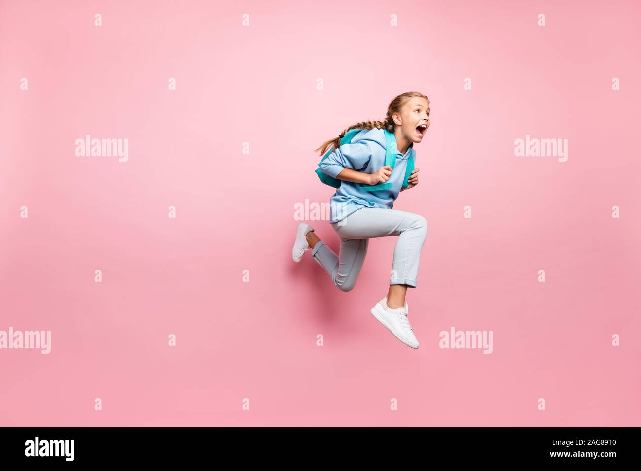 Volle Länge Körper Größe gedreht Foto von Angst Angst Mädchen weg laufen in Angst mit Rucksack hinter trägt blaue sportlicher Verschleiß sweatshirt jeand Stockfoto