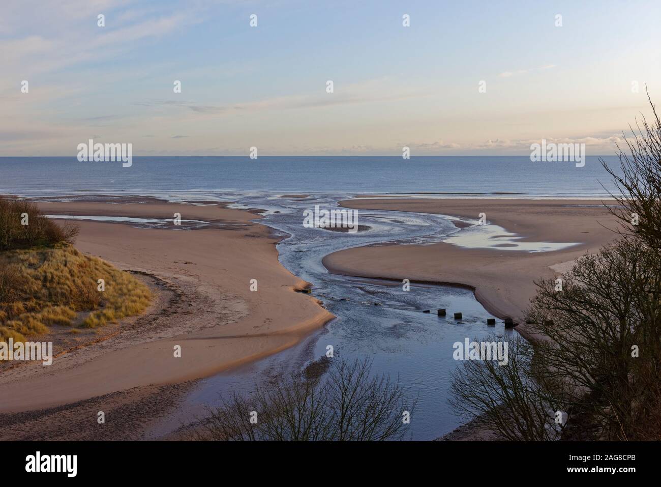 Der Mund der Lunan Wasser über den Strand in Lunan Bucht und in der Nordsee auf einem kalten Dezember Morgen. Stockfoto