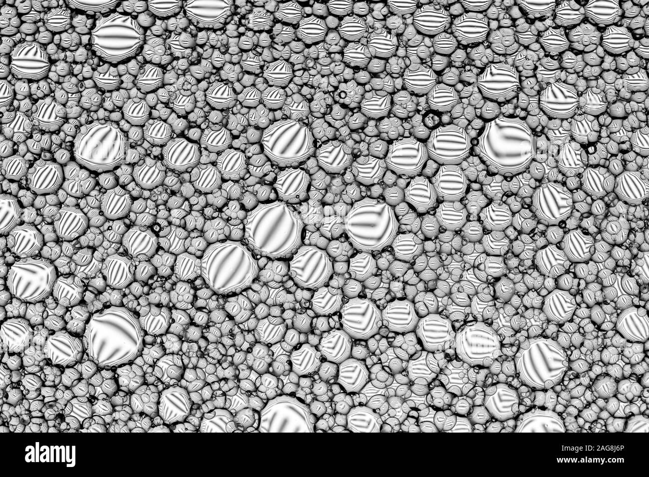 Ansicht von oben auf den Schwarzen und Weißen Tropfen Öl auf dem Wasser. Kreise und Ellipsen. Monochrome abstrakt Hintergrund für Design mit Spiegeln gebrochen wird. Stockfoto