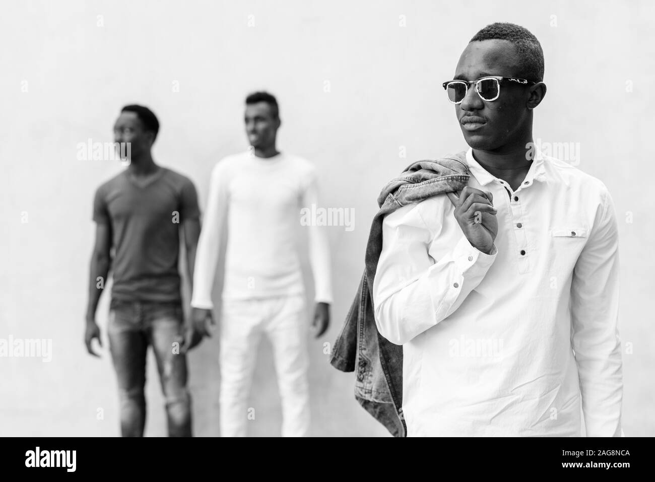 Drei junge afrikanische Männer hängen heraus gegen die Betonwand im Freien Stockfoto