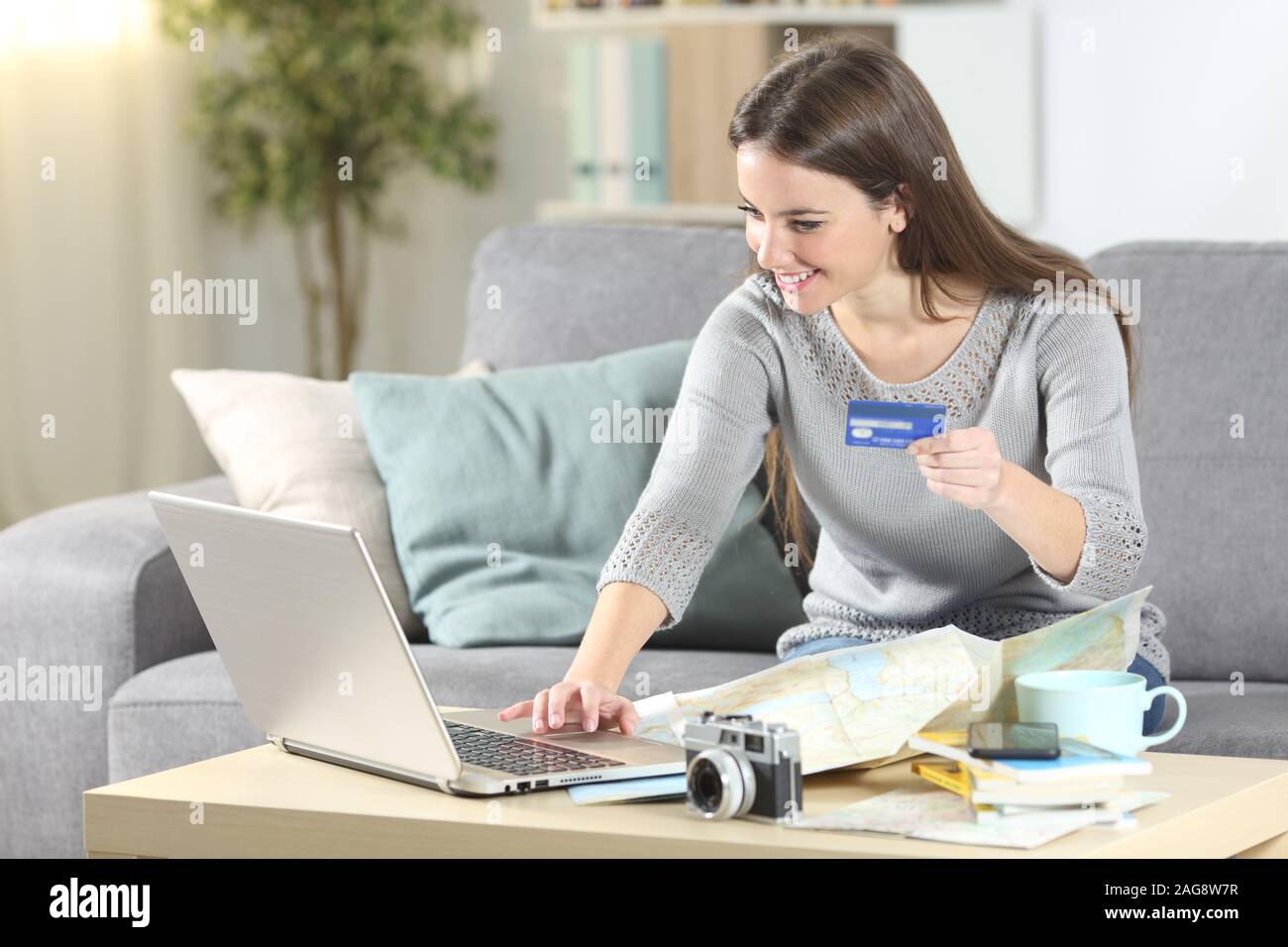 Ihnen gerne touristische Zahlen Sie Online mit Kreditkarte und Laptop Planung Urlaub auf einer Couch im Wohnzimmer zu Hause sitzen Stockfoto