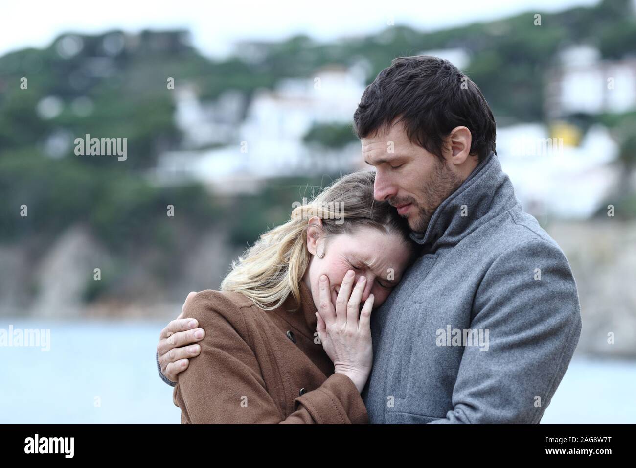 Besorgt man beruhigend eine traurige Frau im Winter am Strand Stockfoto