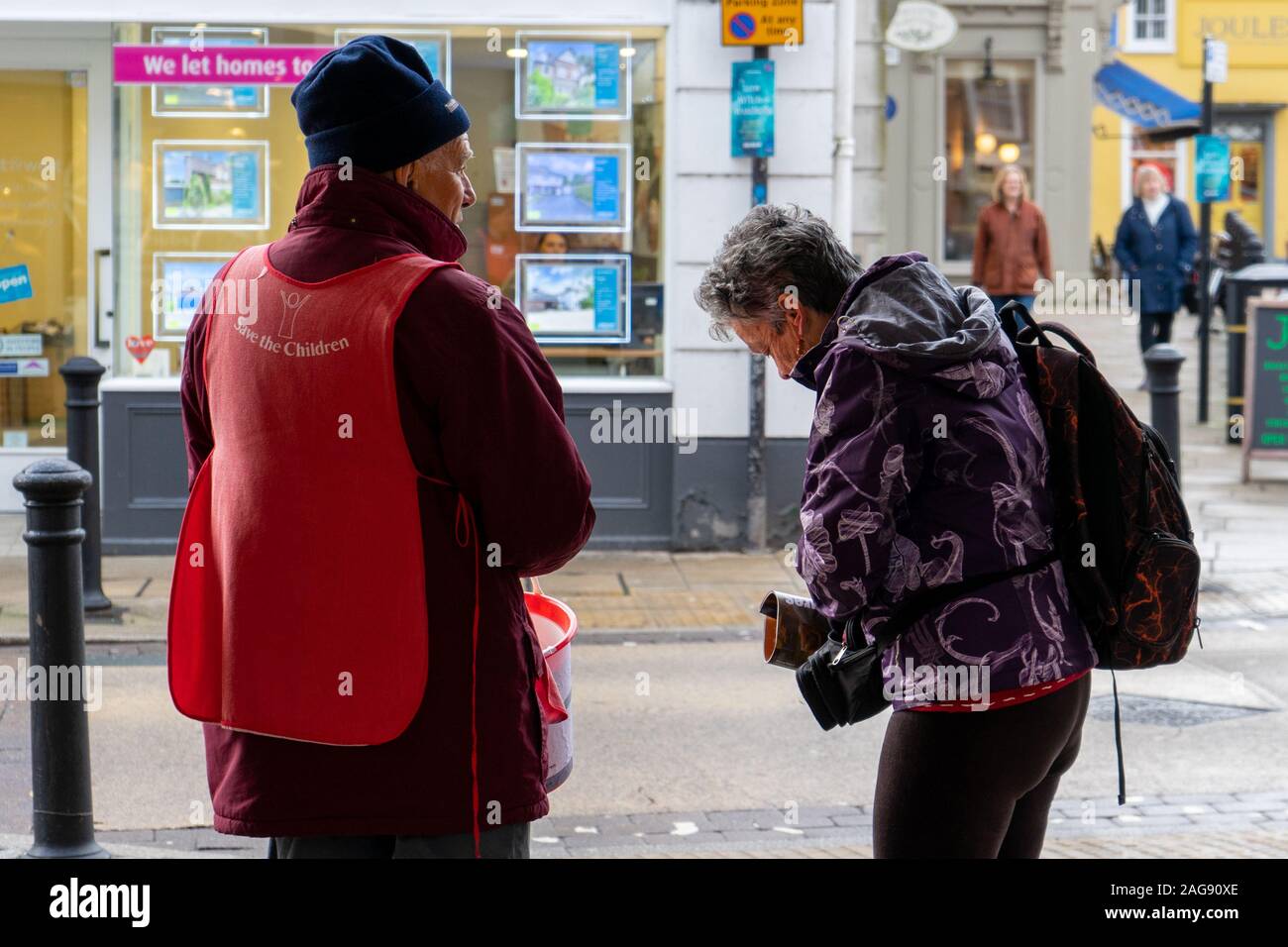 Eine Frau mittleren Alters Münzen erhalten von ihrem Geldbeutel an eine Wohltätigkeitsorganisation Sammler in der Straße zu geben Stockfoto