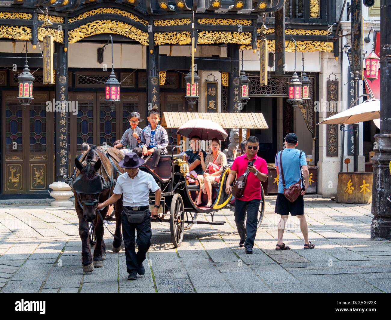 HAINAN, CHINA - 3 Mar 2019 - Eine Asiatische chinesische Familie ein Pferd buggy Fahrt am Feng Xiao Gang Film Stadt in Hainan, eine beliebte Theme Park. Stockfoto