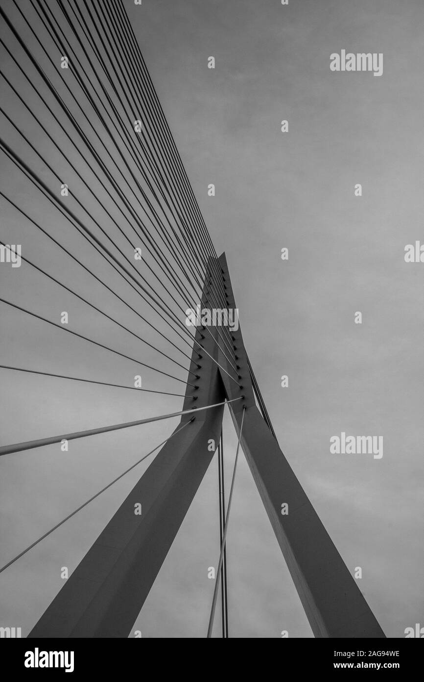 Vertikale Graustufenaufnahme einer Hängebrücke unter der Bewölkung Himmel Stockfoto