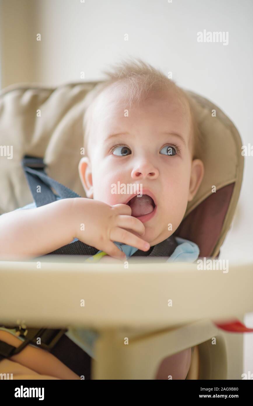 Baby kauen auf Ihre Finger und sieht irgendwo Stockfoto