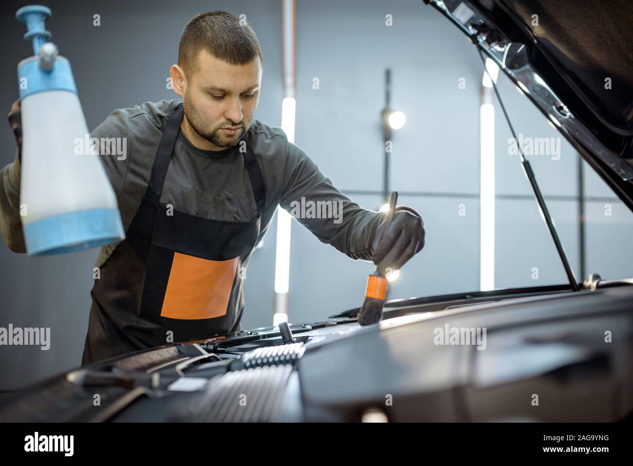Mann führt eine professionelle Reinigung, Waschen Motor mit Pinsel und Waschmittel in der Service-station Stockfoto