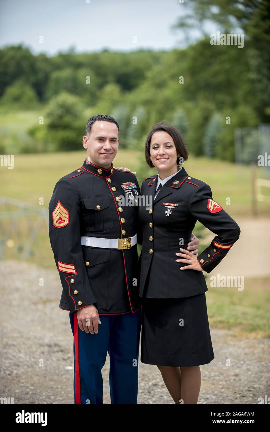 Vertikale Aufnahme eines Militärpaares, das sich umarmt, während es lächelt Die Kamera Stockfoto