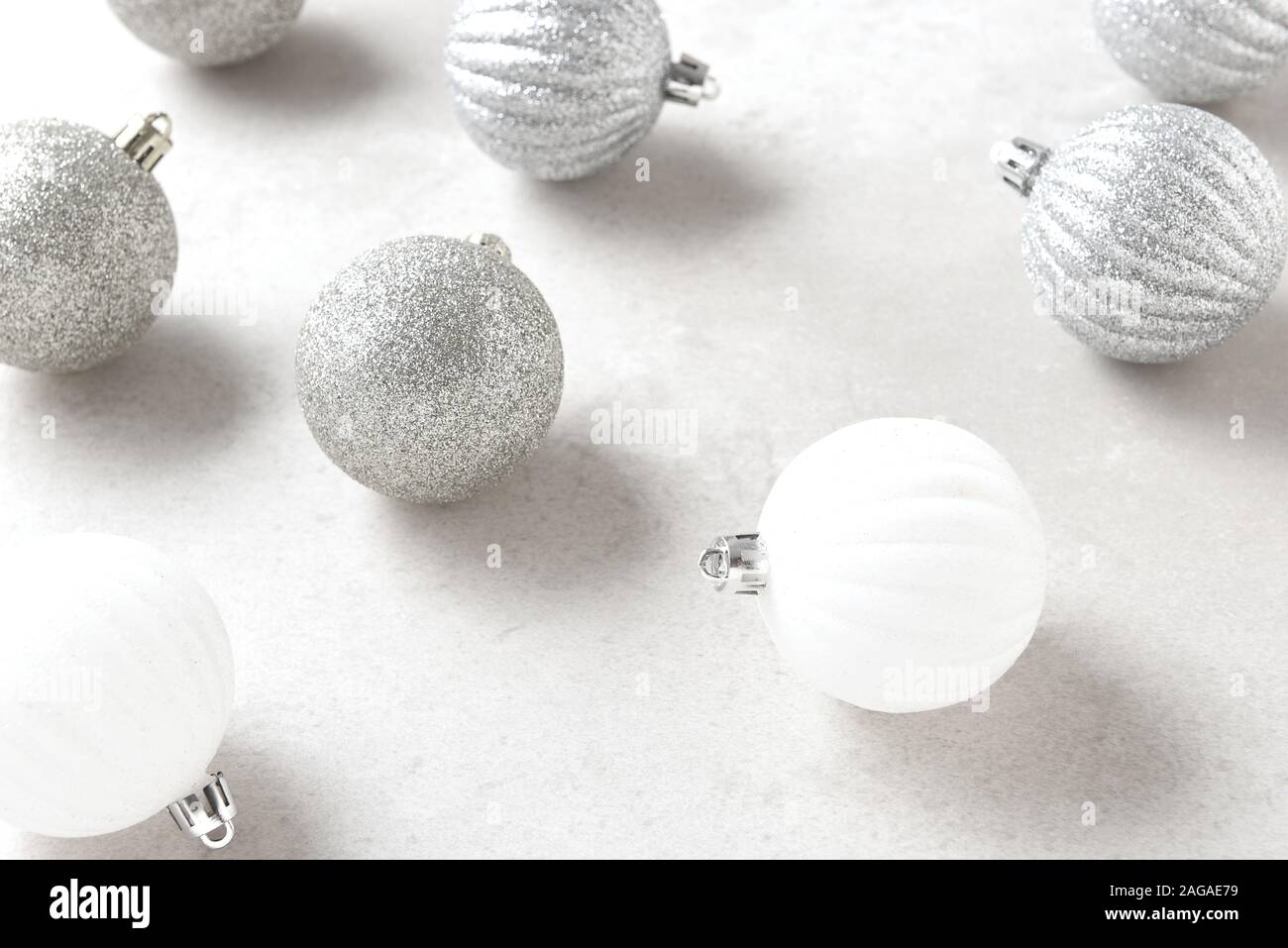 Christbaumschmuck closeup mit geringer Tiefenschärfe. Weiß und Silber Kugeln auf einem hellgrauen Table Top. Stockfoto