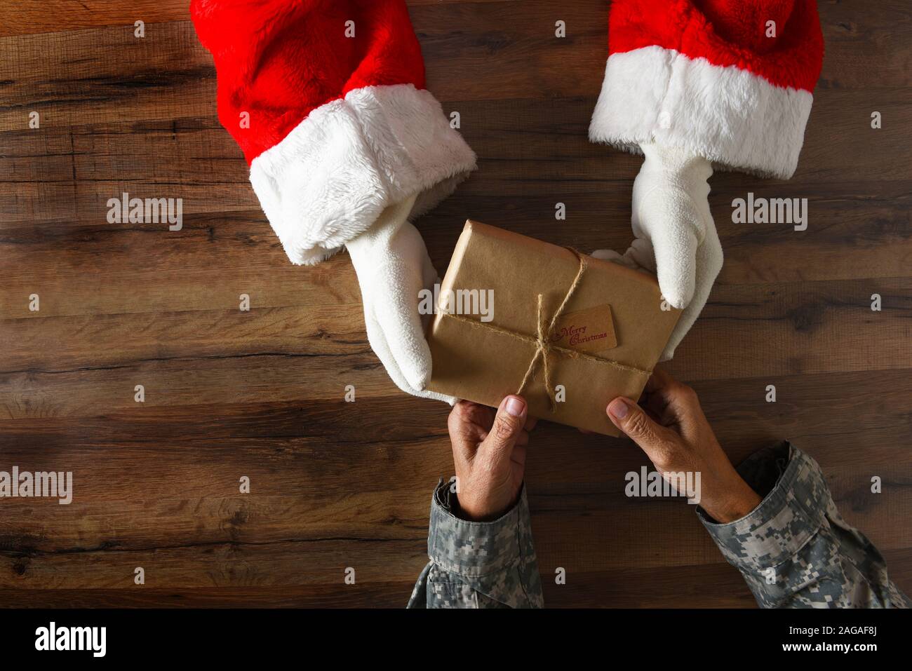 Santa Claus Übergabe einer einfachen eingewickelt zu Weihnachten ein Soldat. High Angle Shot nur mit Händen und Armen sichtbar. Stockfoto