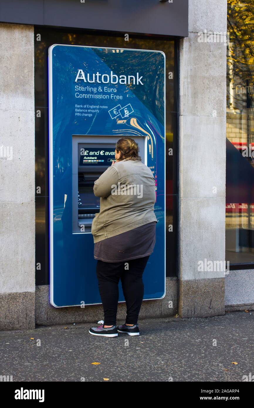 16. Oktober 2019 Eine übergewichtige junge Frau, die ein ATM in der geschäftigen Donegall Square West Belfast Nordirland. Stockfoto