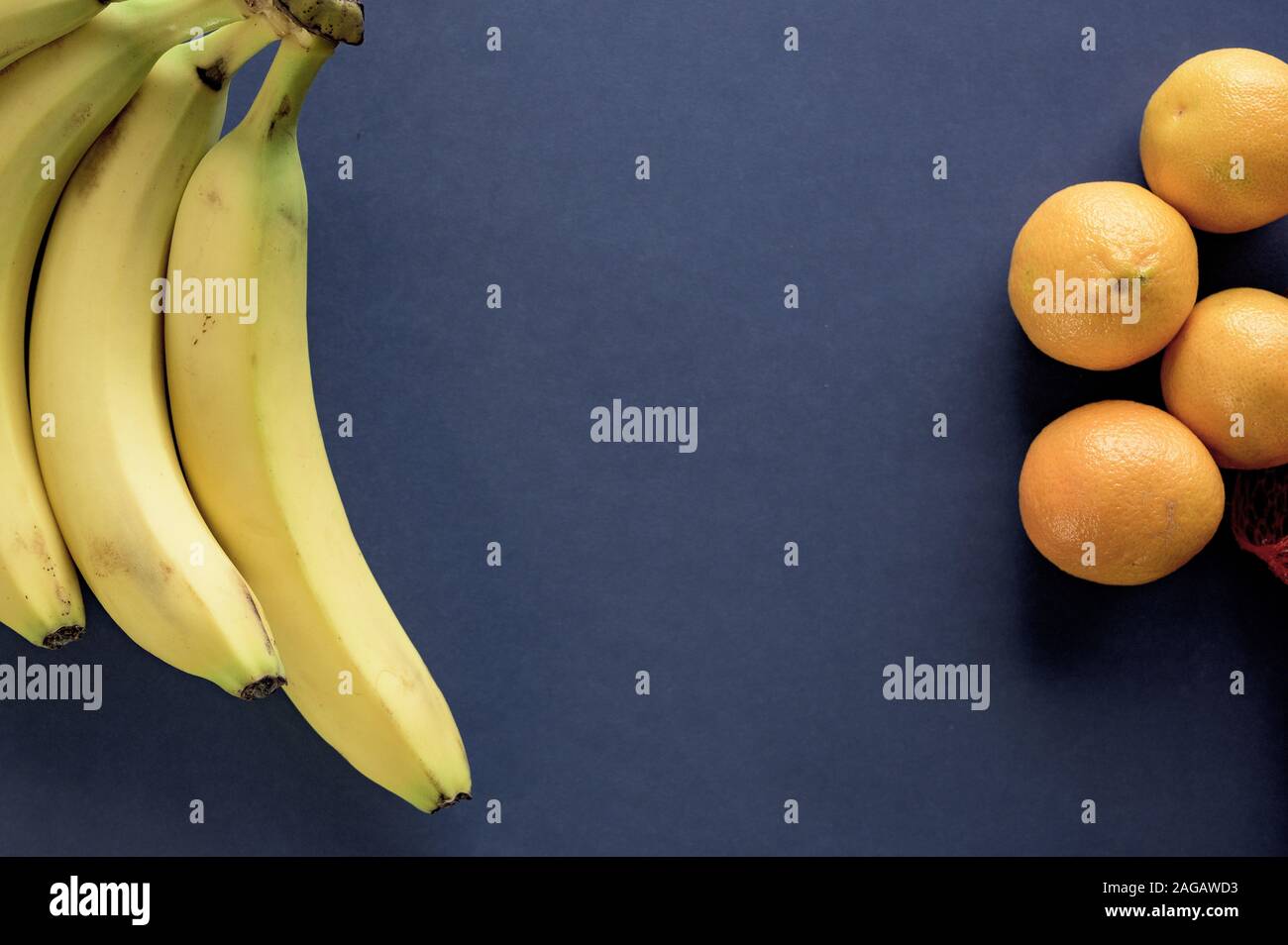 Dunkelblaue Oberfläche mit Bananen und Orangen an den Seiten Stockfoto