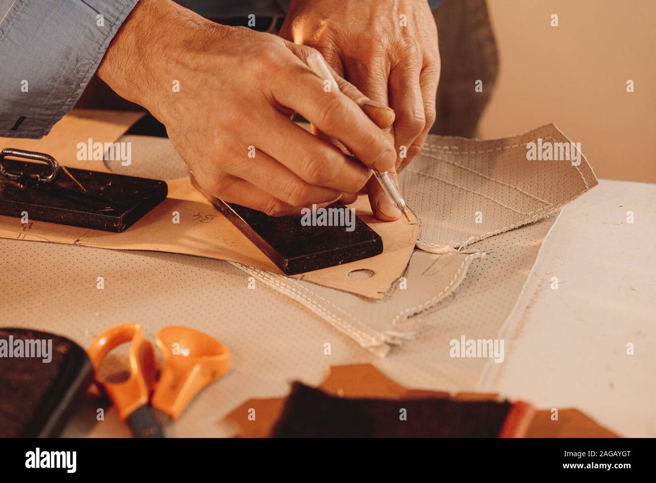 Leatherworker Herstellung einer Lederbekleidung mit weißem Stoff in einem studio Stockfoto