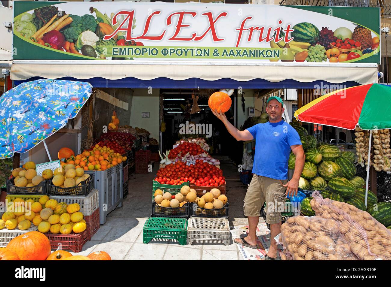 Obst und Gemüse Verkäufer zeigt eine PUMKIN an seinem Geschäft, Zakynthos - Stadt, Insel Zakynthos, Griechenland Stockfoto