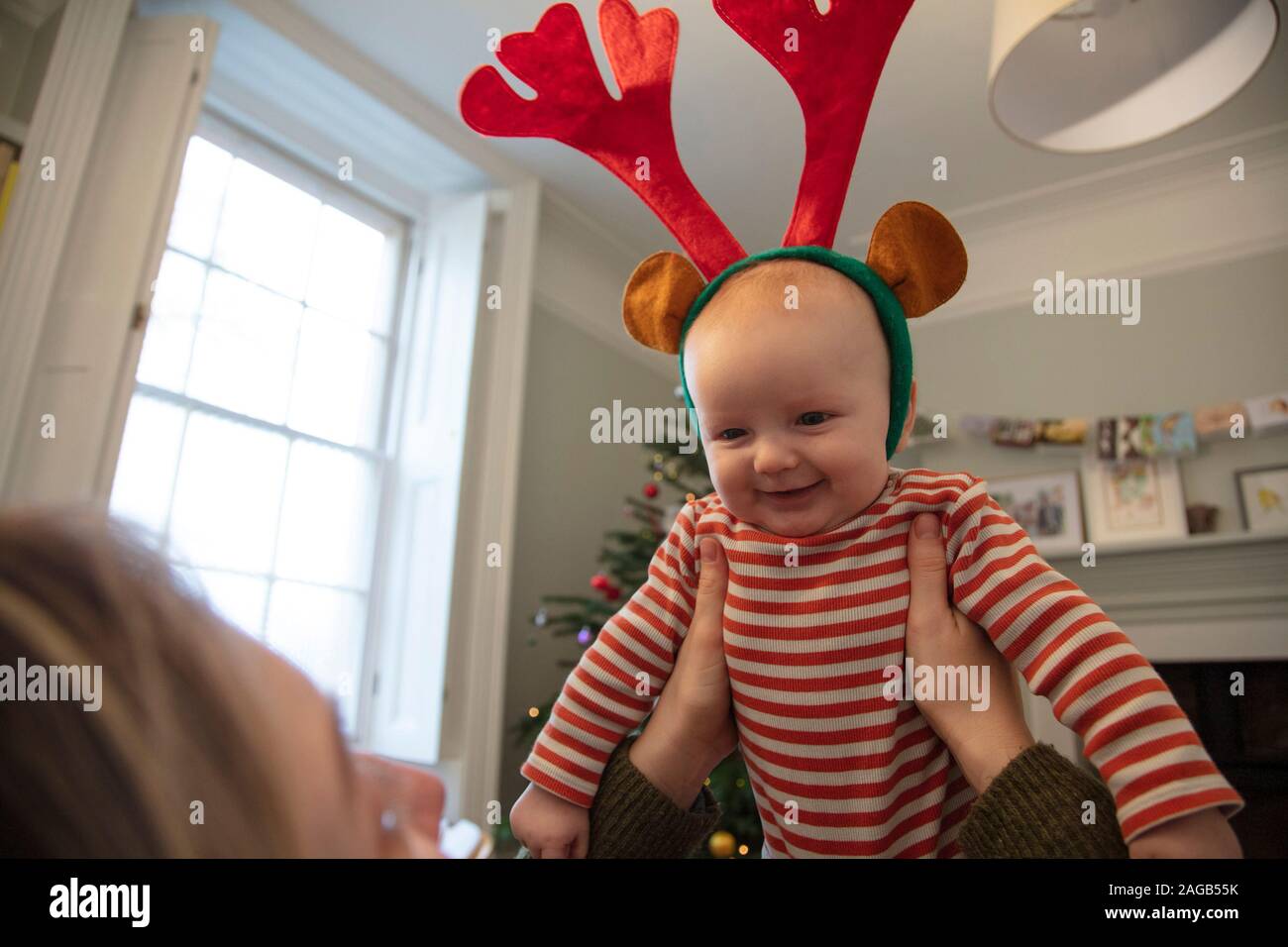 Cute Baby tragen festliche Rentier Geweih spielen mit Mama an Weihnachten Stockfoto