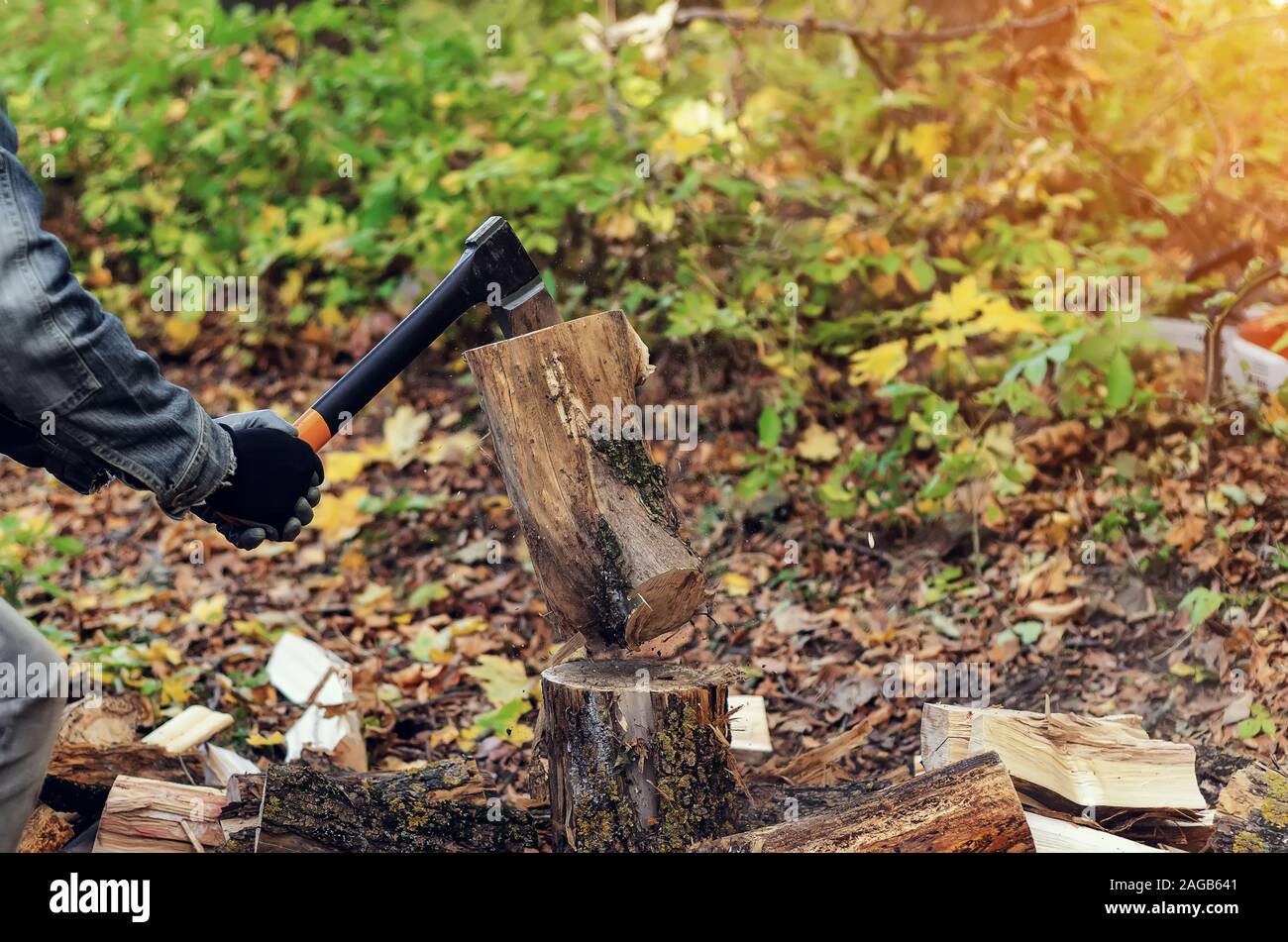 Mann hält eine industrielle Ax. Die Axt in den Händen. Ein starker Mann hält eine Axt in der Hand auf einem Hintergrund von Wald, Brennholz. Ein Mann Holzfäller mit einer Stockfoto