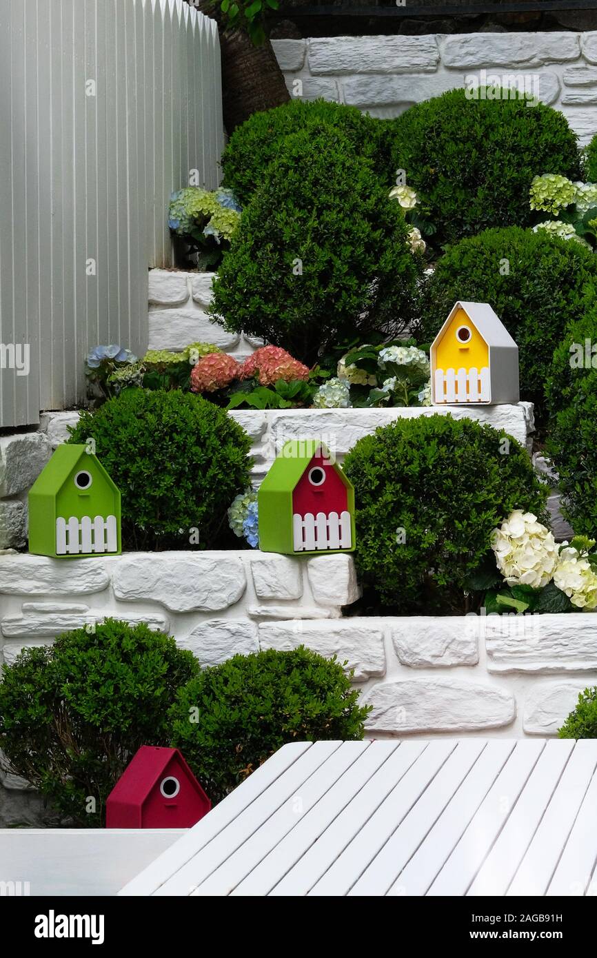 Landschaftsgestaltung in Garten. Garten mit Sträuchern, blühende Pflanzen und bunten Häusern eingerichtet Stockfoto