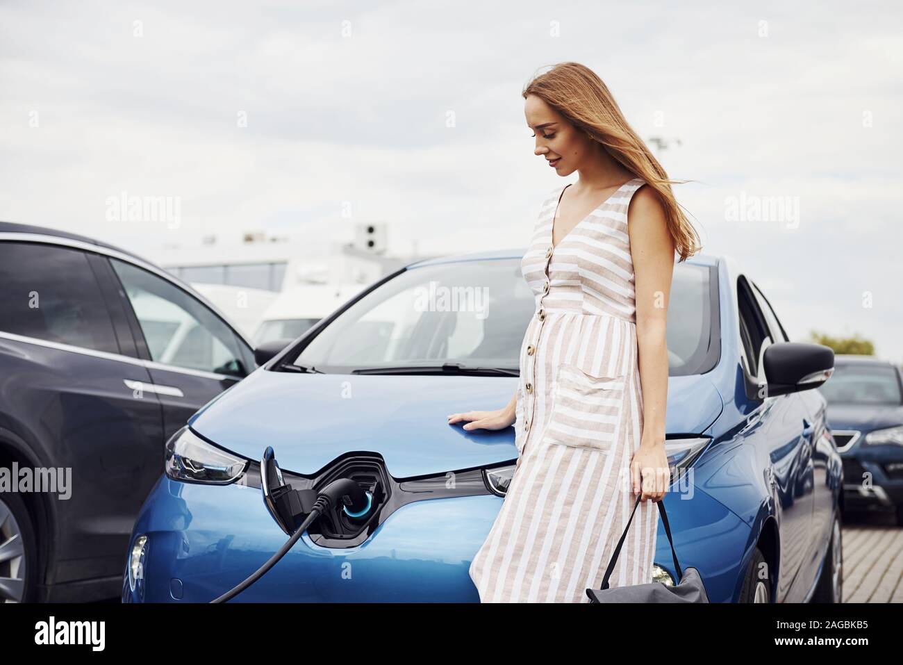 Bewölkten Tag. Frau auf der Elektroautos Ladestation bei Tag. Neues Fahrzeug Stockfoto