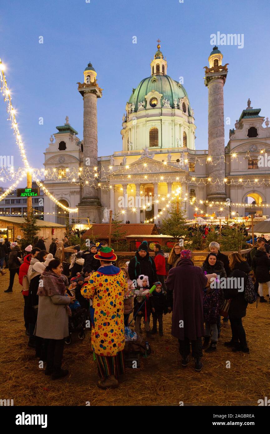 Wiener Weihnachtsmarkt - Menschen auf dem Markt von Karlsplatz vor der St Charles Kirche (Karlskirche), bei Sonnenuntergang, Wien Österreich Europa Stockfoto