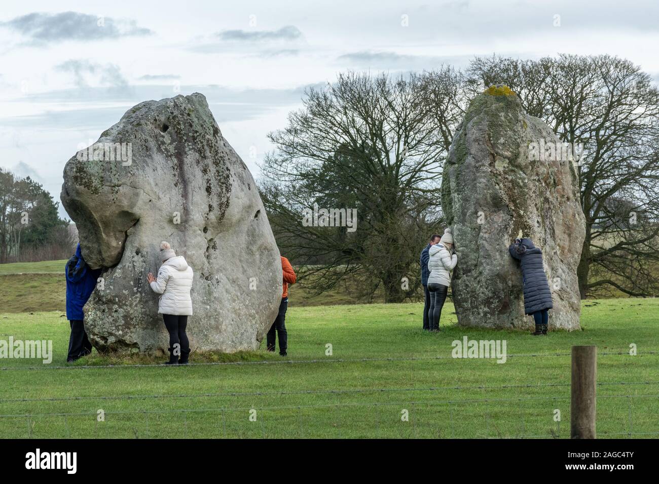 Besucher in Avebury Stone Circle berühren und umarmen die neolitihic Steine für die magnetische Energie und Heilkraft, Wiltshire, England, Großbritannien Stockfoto