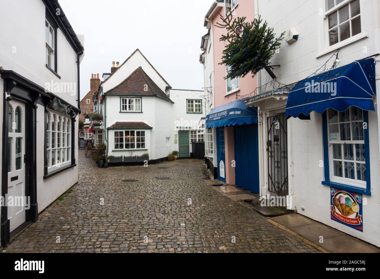 Malerische alte Geschäfte und Gebäude auf einer gepflasterten Straße im Dezember Lymington, Hampshire, England, Großbritannien Stockfoto