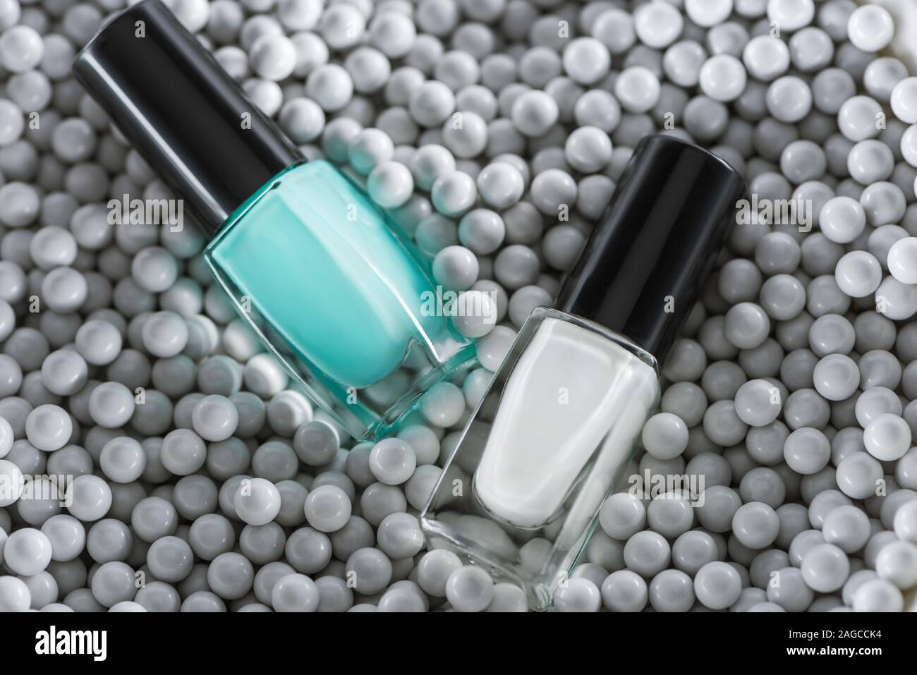 Blick von oben auf die blauen und weißen Nagellack in Flaschen in grau Zierperlen Stockfoto