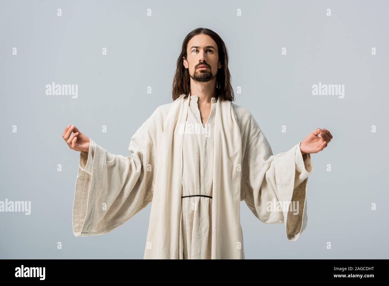 Religiöse Menschen in Jesus Gewand mit ausgestreckten Händen isoliert auf Grau Stockfoto