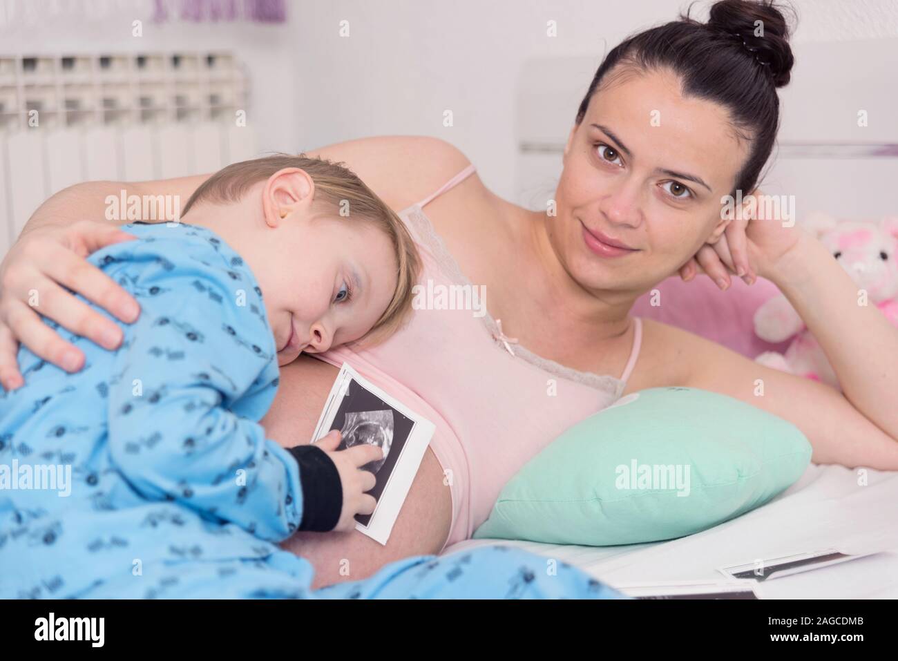 Neugierig schön darkeyed junge Gefühl sehr interessiert, während playingwoth seine schwangere Mutter. Bitte warten, bis die kleine Schwester. Stockfoto