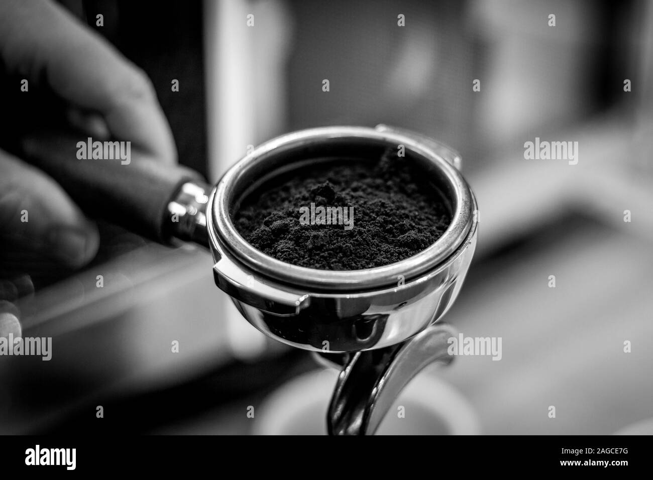 Eine schwarze und weiße Nahaufnahme portrait einer portafilter voller Kaffee aus frisch gemahlenen Kaffeebohnen. Stockfoto