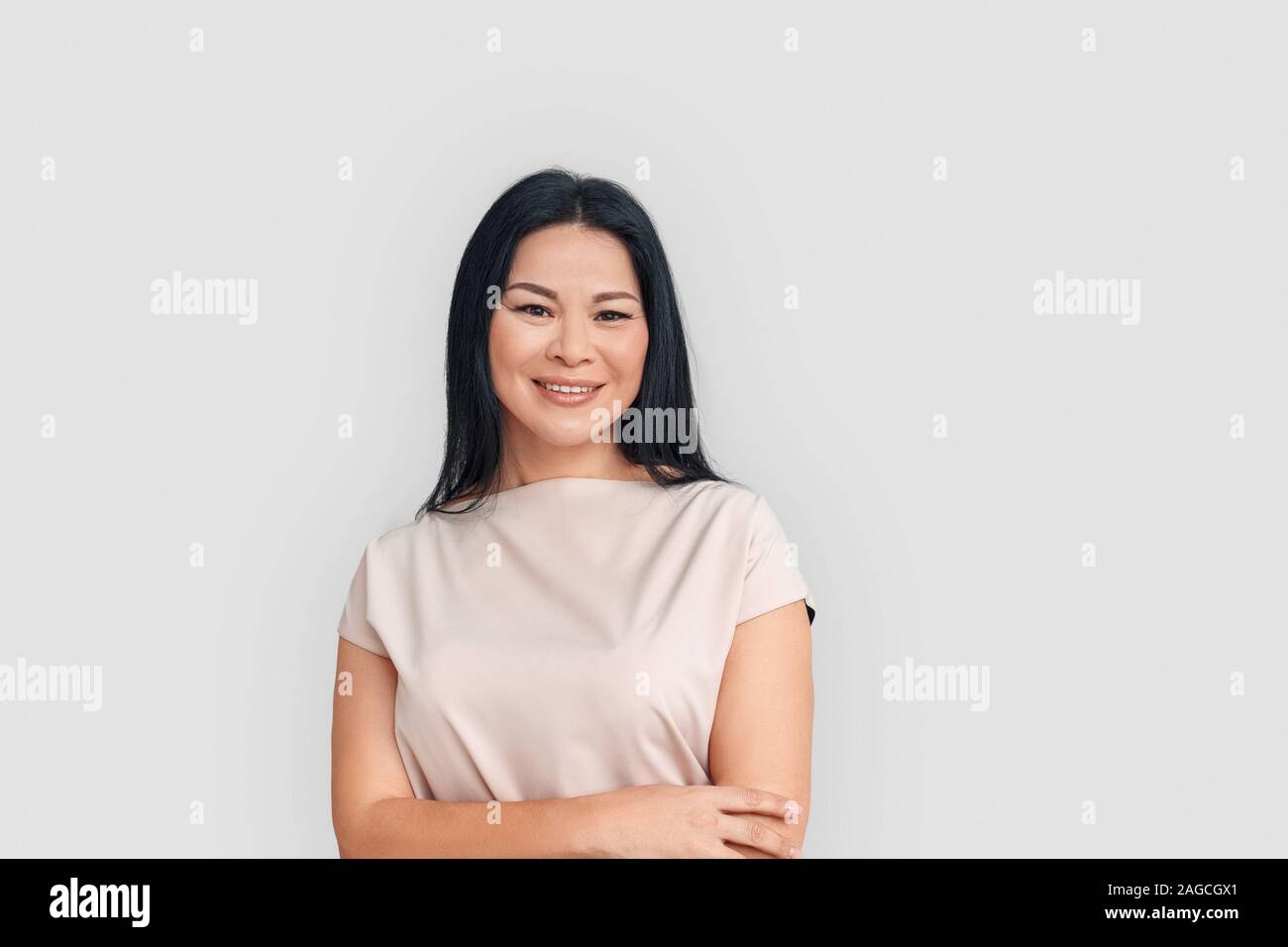Freestyle. Asiatische Frau, die isoliert auf weißem verschränkte Arme lächelte zuversichtlich Stockfoto