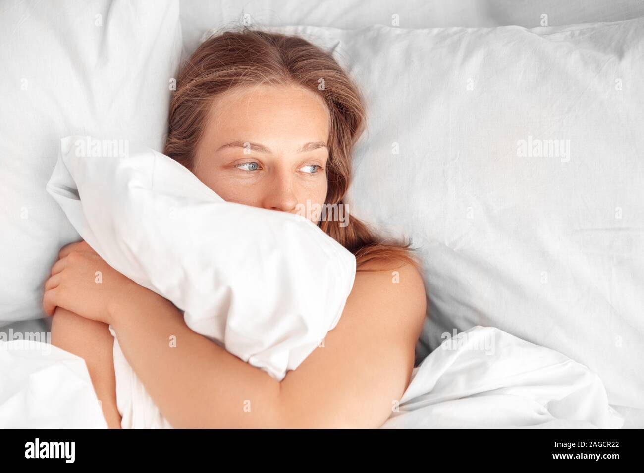 Morgens zu Hause. Liegende Frau auf dem Bett und umarmte Decke schläfrig Top View close-up Stockfoto