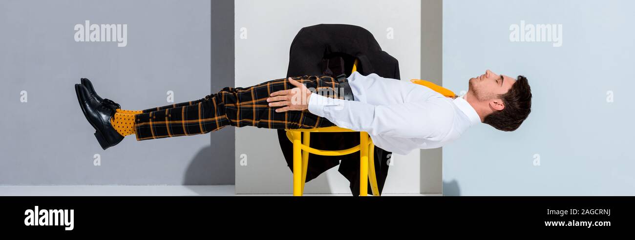 Panorama-aufnahme des Menschen in karierten Hosen liegen auf gelben Stuhl weiß und grau Stockfoto
