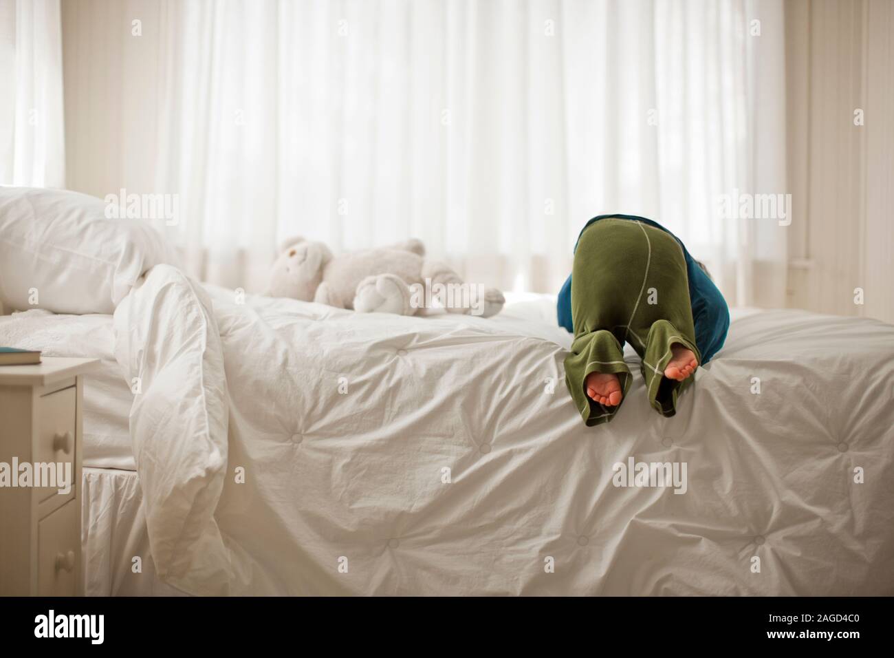 Junge Junge spielt auf einem Bett in einem Schlafzimmer. Stockfoto
